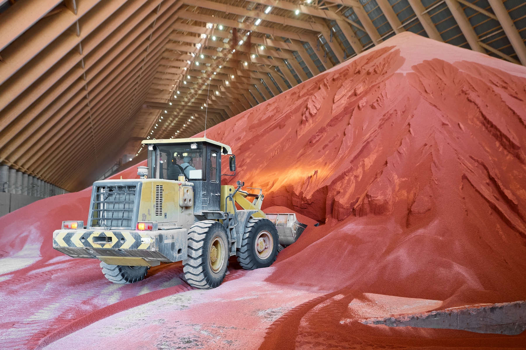 Earth moving equipment in a mine warehouse moves red coloured material